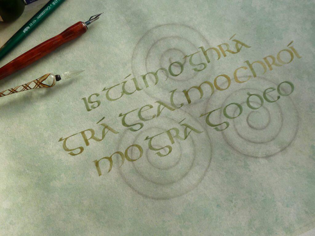 Unique calligraphy design. Gentle green and silver background with the triple spiral. To the foreground half-uncial script in gold and green. 