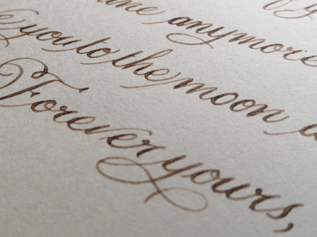 Close-up of overlapping brown and sepia cursive handwriting on ivory coloured paper.