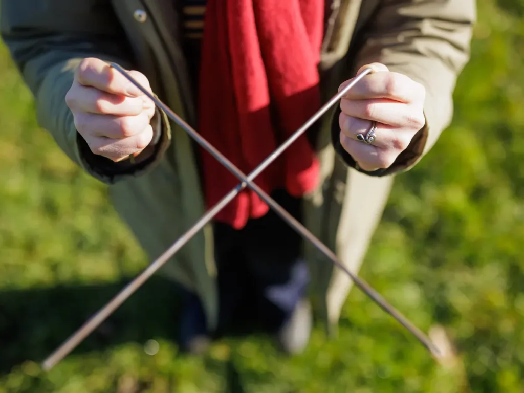 Images shows a person holding brass divining rods. Dowsing for water.