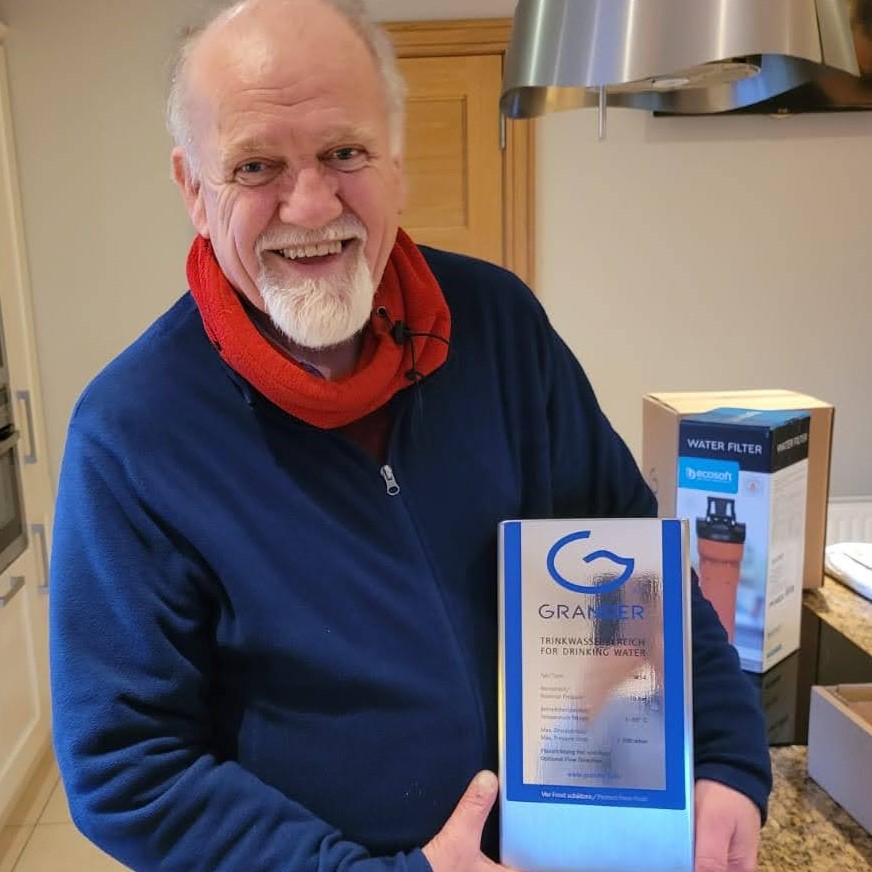 Photograph of Douglas Gordon. Natural Scientist, Diviner and Entrepreneur. Pictured holding a Grander Whole House Water Revitalisation Unit. 