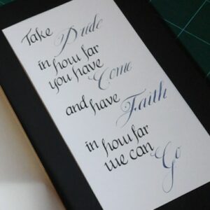Close-up of a handwritten calligraphy note reading, “Take pride in how far you have come and have faith in how far you can go.”