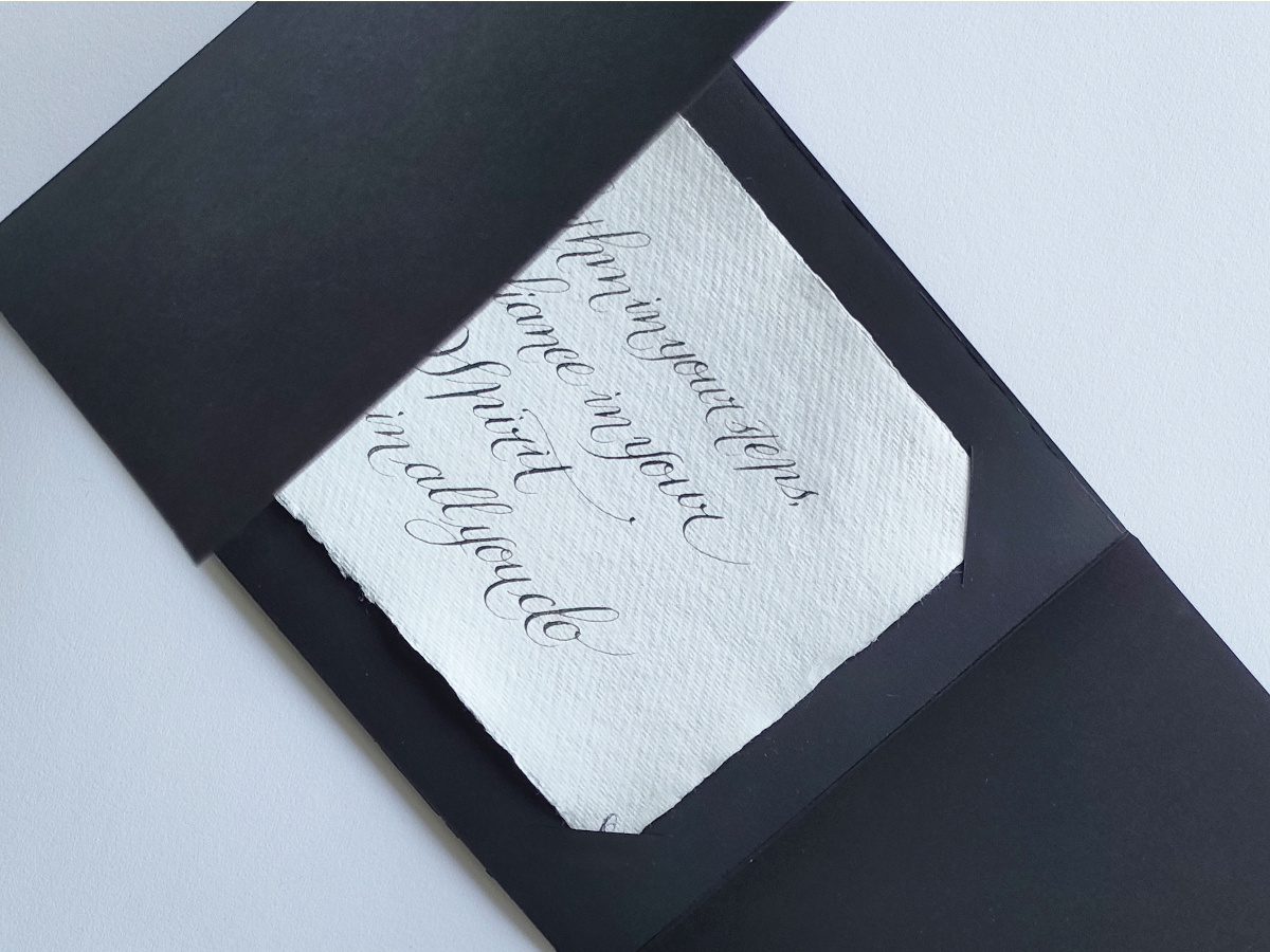 Black gated card with a white textured insert displaying handwritten calligraphy.