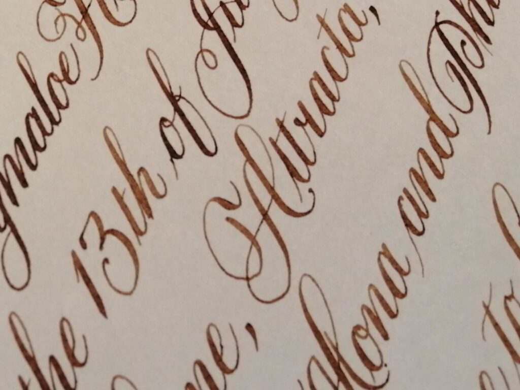 Close-up of overlapping brown and black cursive handwriting on cream-colored paper.