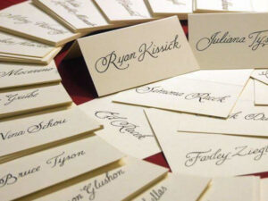 Cream-colored calligraphy place cards with names scattered across a table.